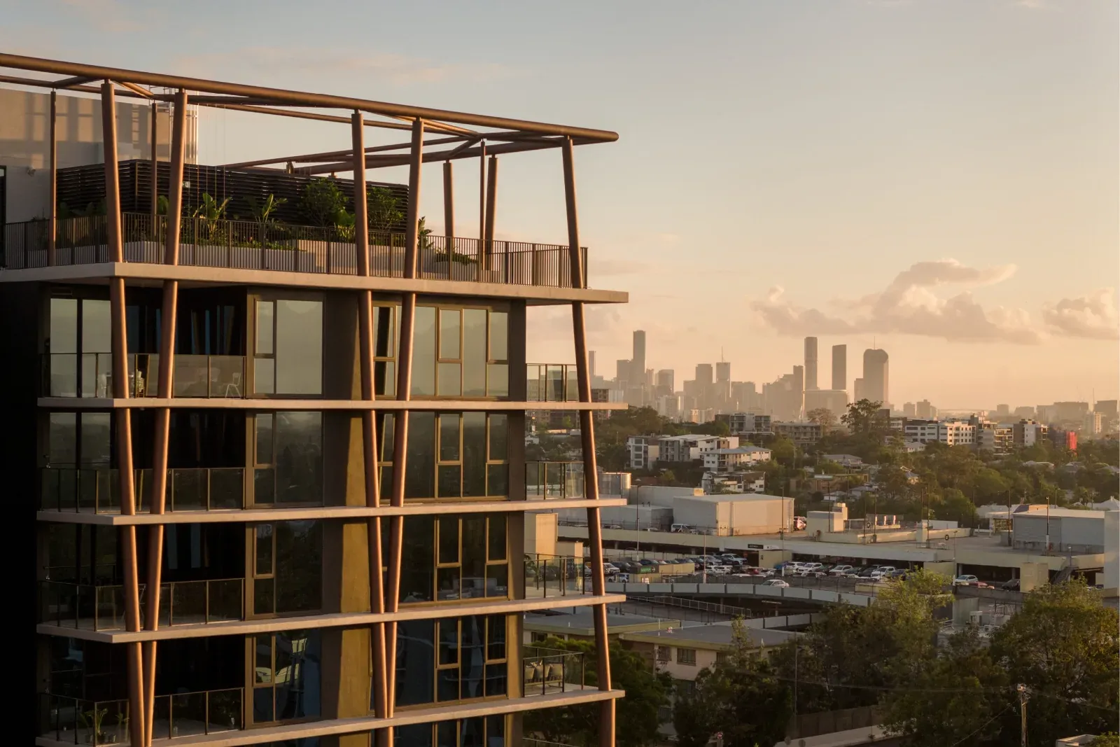 The Witton apartment tower in Indooroopilly at sunset with the Brisbane skyline behind